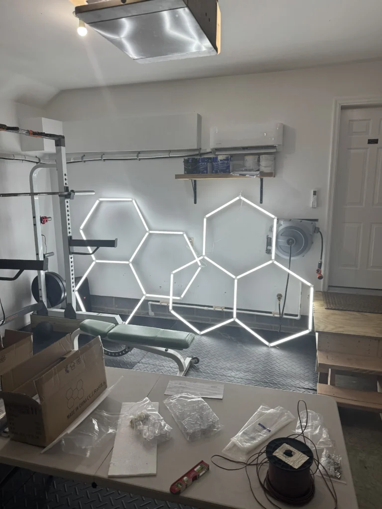 Hexagonal LED lights sitting on the floor of a garage being tested