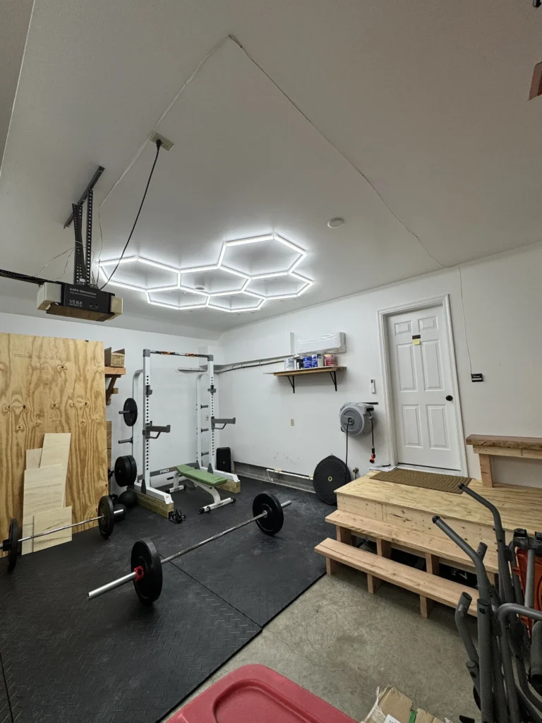 Hexagonal LED lights mounted to the ceiling of a home garage/gym